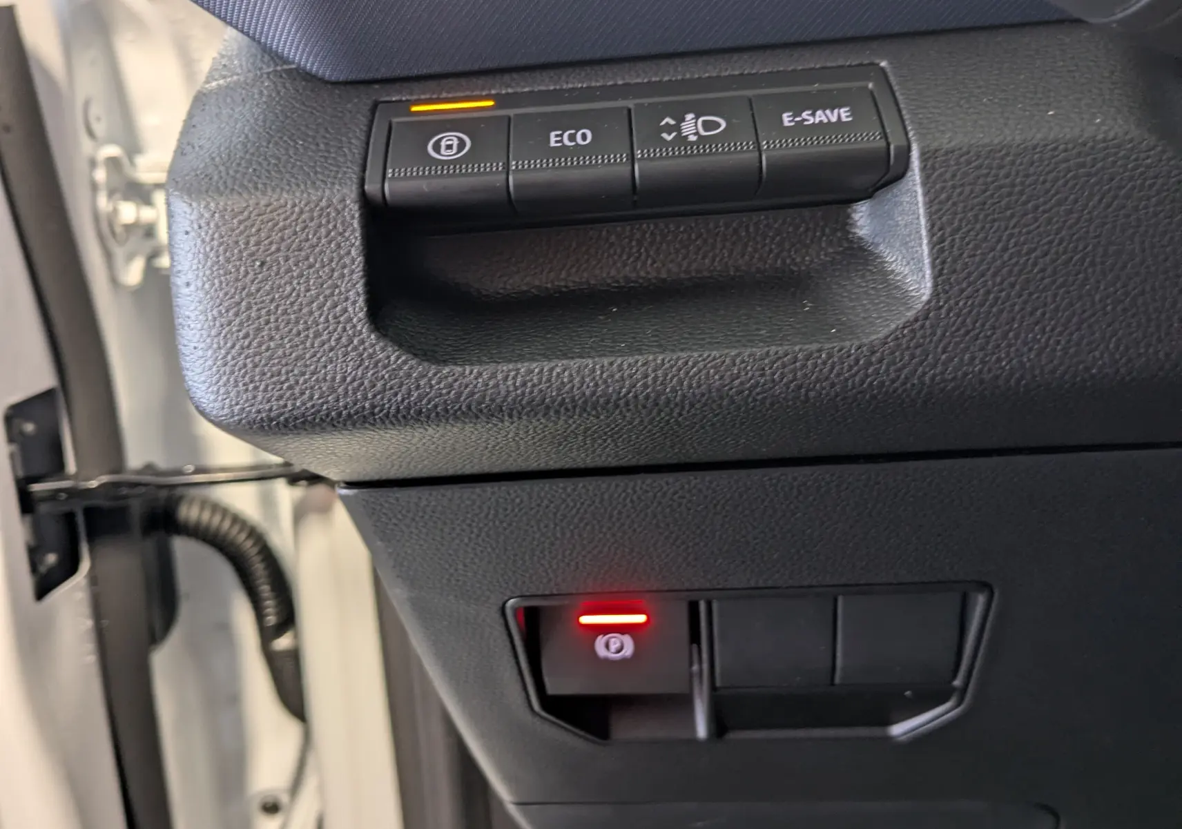 Gros plan sur les commandes côté gauche du tableau de bord du Dacia Duster blanc glacier, avec boutons ECO et frein à main électrique allumés.