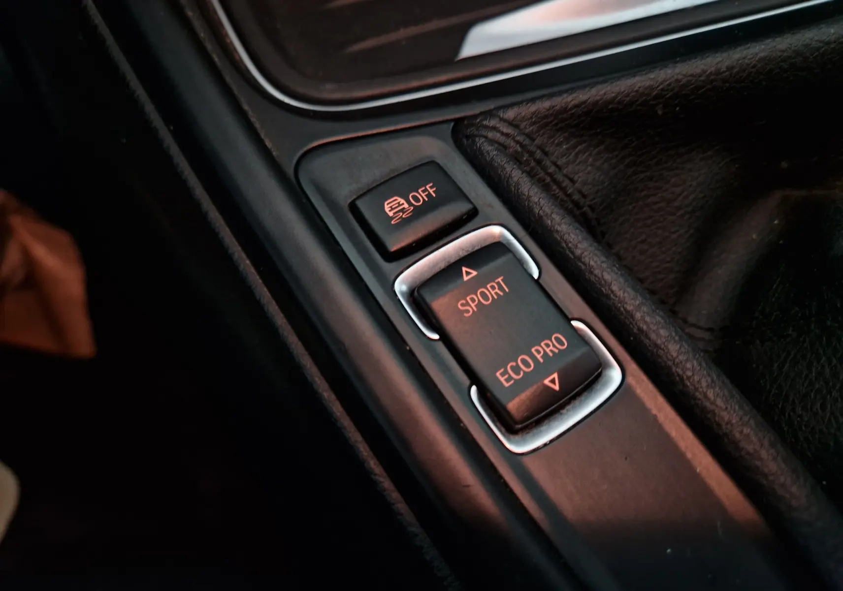 Gros plan sur les commandes de mode de conduite Sport et Eco Pro dans l'habitacle noir d'une BMW Série 3 316D 2014.