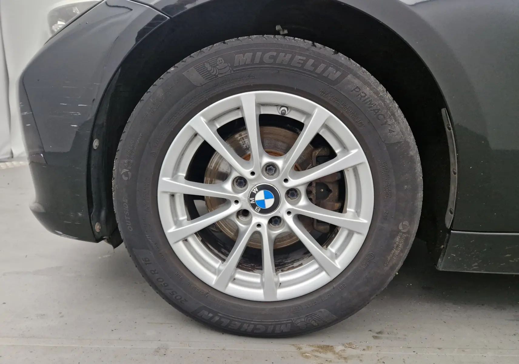 Gros plan sur la roue avant gauche noire d'une BMW Série 3 316D 2014 avec jante alliage argent et pneu Michelin.