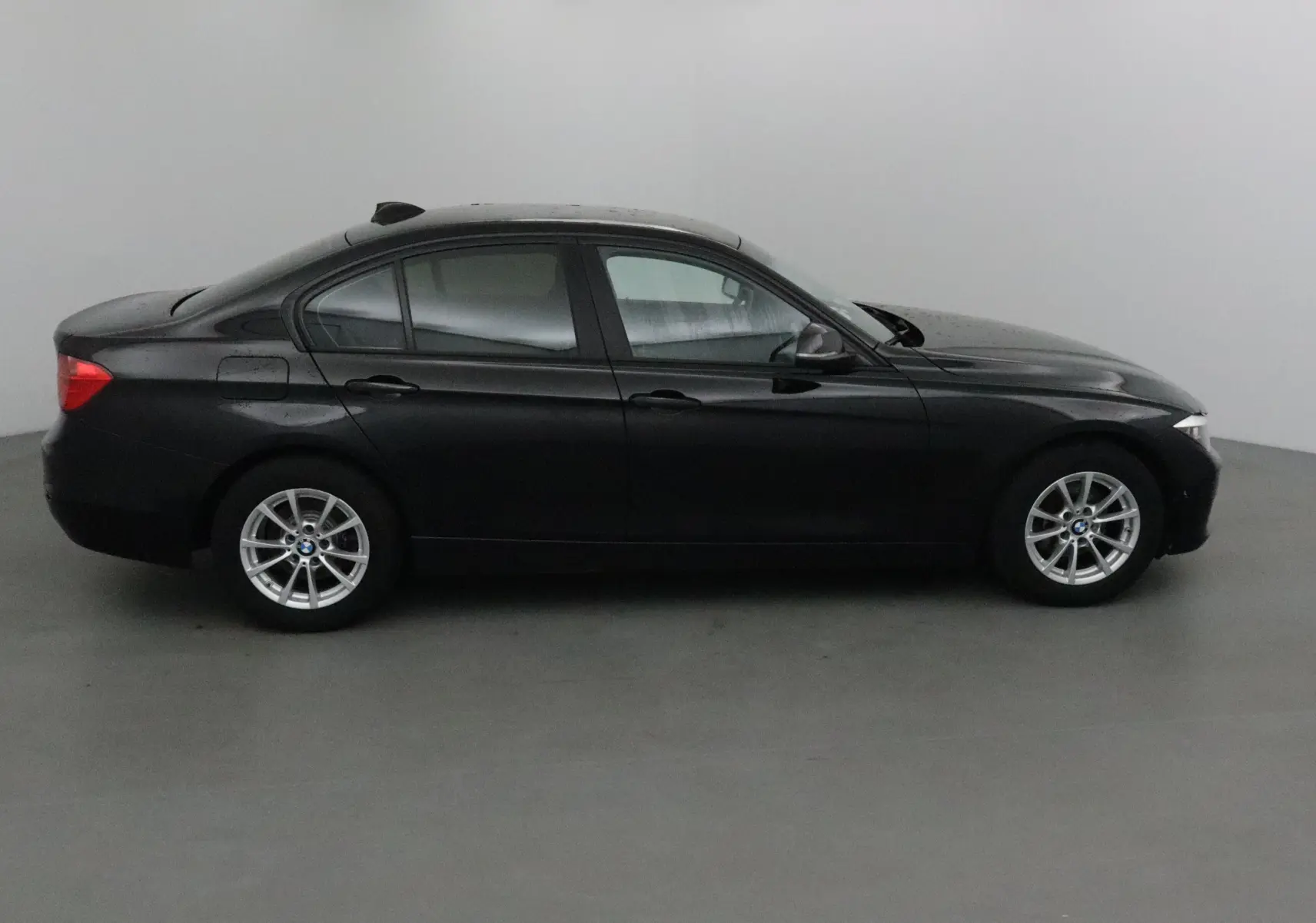 Profil côté gauche d'une BMW Série 3 316D noire de 2014 avec jantes alliage et rétroviseurs électriques.