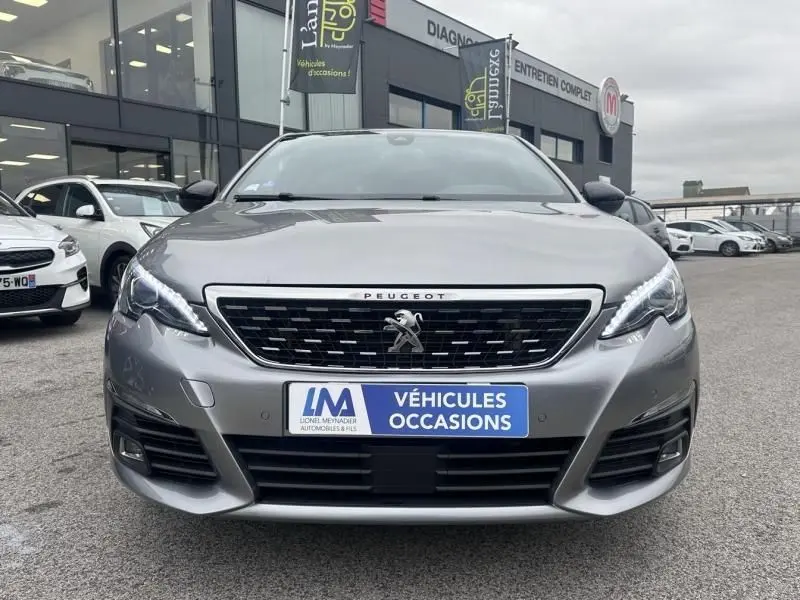 Vue frontale d'une Peugeot 308 gris métal de 2019, avec calandre noire et logo lion au centre, en concession.