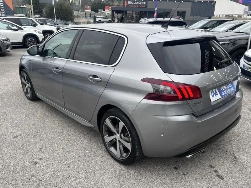 Peugeot 308 gris métal vue 3/4 arrière droit, feux arrière LED distinctifs et jantes alliage sport.