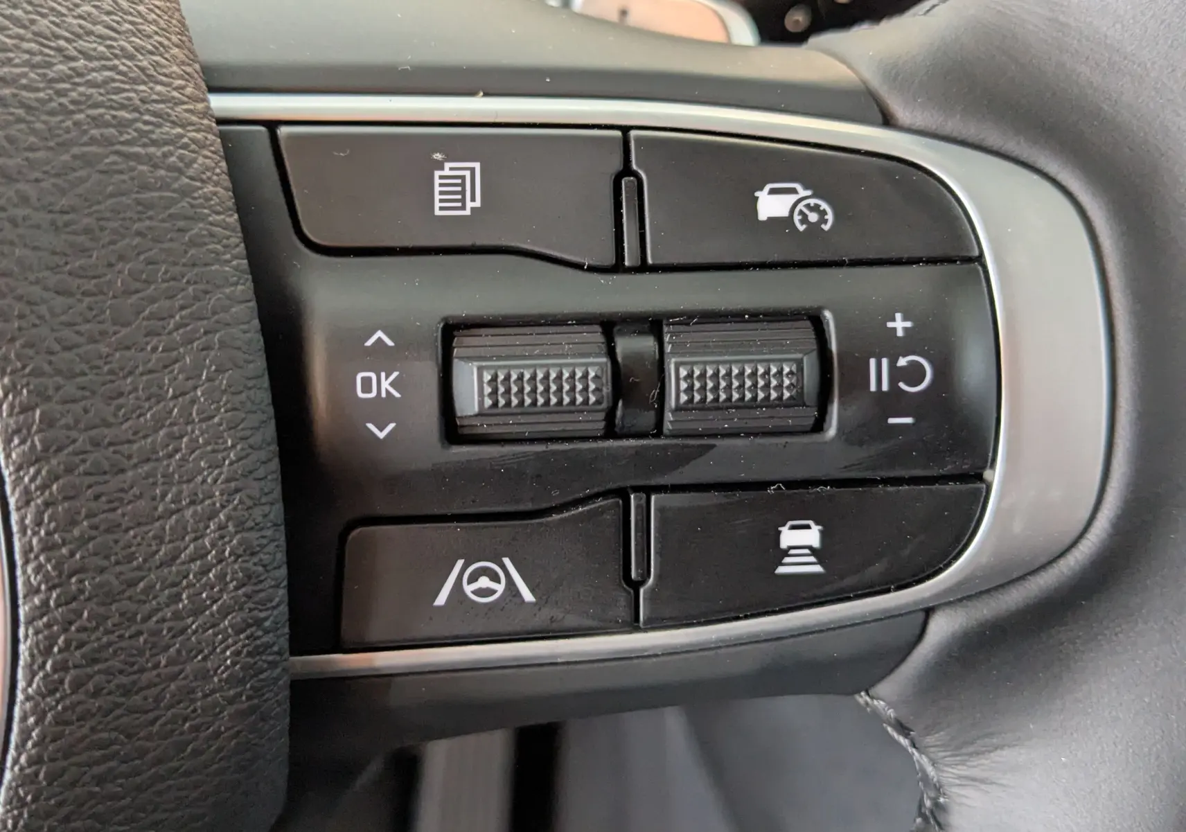 Gros plan sur les commandes multifonctions noires du volant du Kia Sportage 2025, avec boutons de régulateur de vitesse et assistance à la conduite.