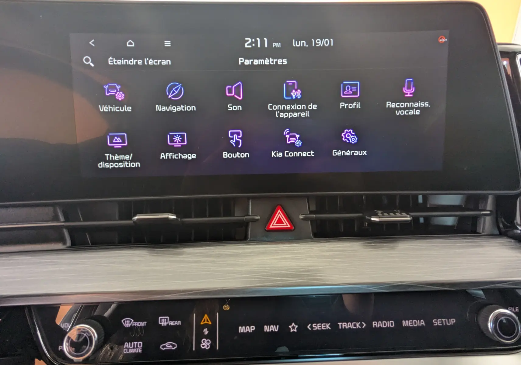 Écran tactile central du Kia Sportage 2025 affichant le menu paramètres, avec commandes climatisation et hazard en dessous.