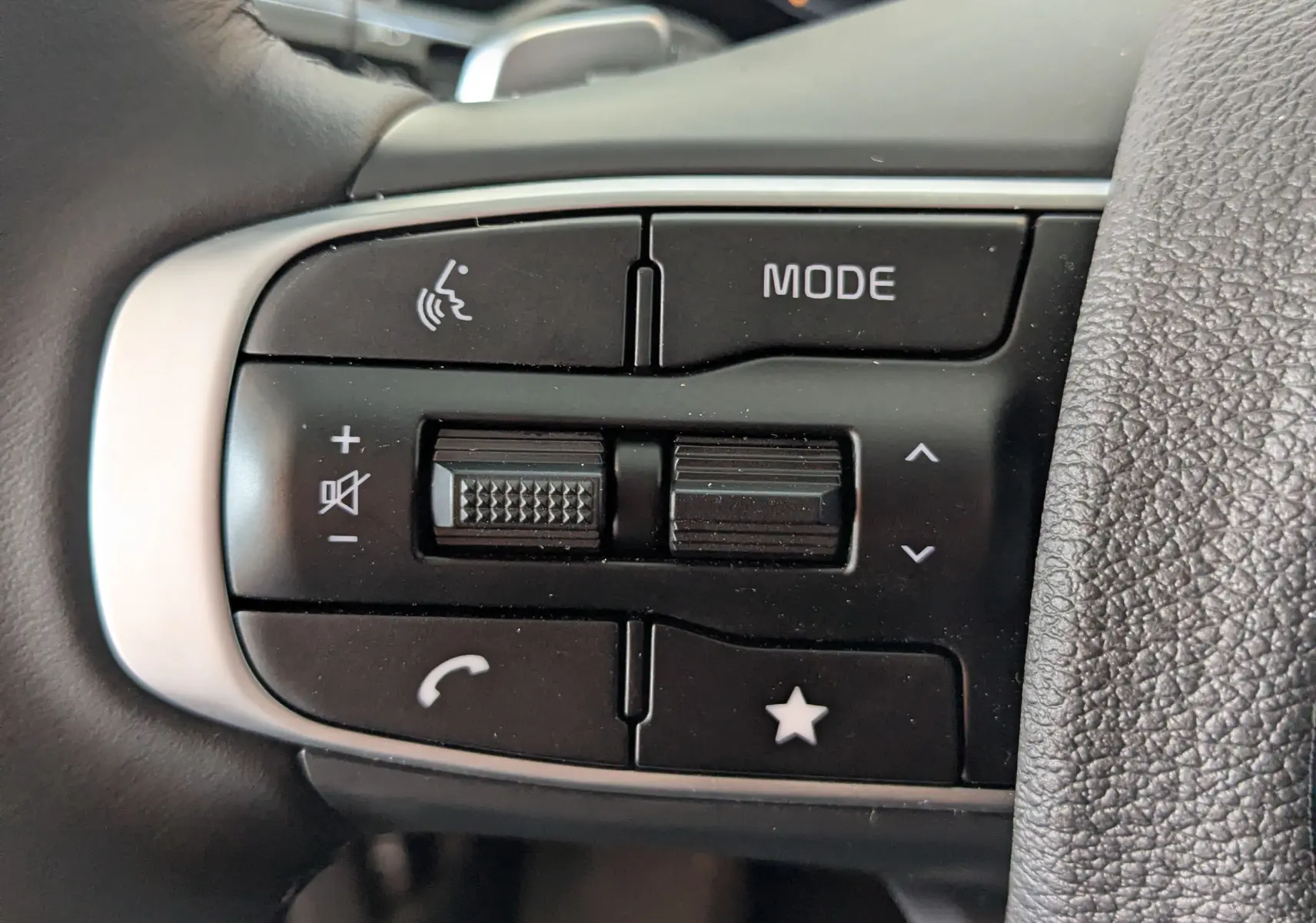 Gros plan sur les commandes multifonctions noires à gauche du volant du Kia Sportage blanc 2025.