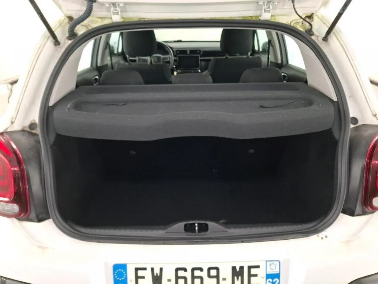 Vue arrière du coffre ouvert d'une Citroën C3 blanche, montrant l'intérieur vide et la tablette cache-bagages noire.