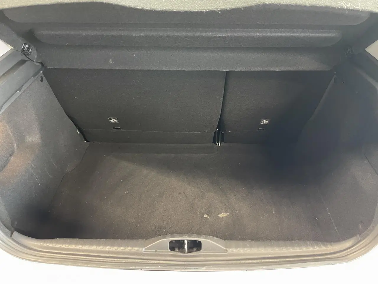 Vue intérieure du coffre noir vide de la Citroën C3 blanche, montrant la banquette arrière rabattue partiellement.