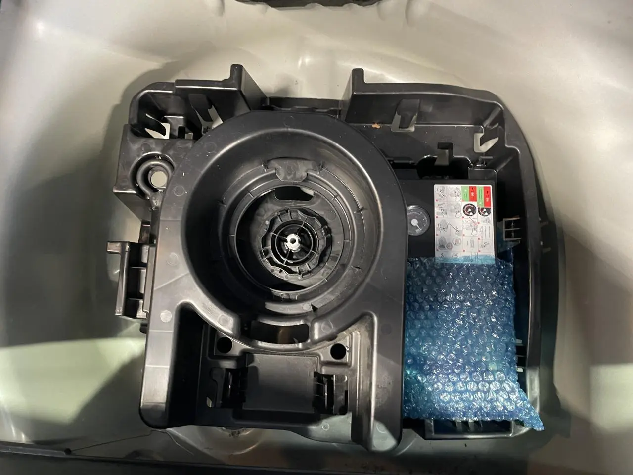 Gros plan sur le compartiment de rangement sous le coffre d'une Citroën C3 blanche, montrant le support de roue de secours.