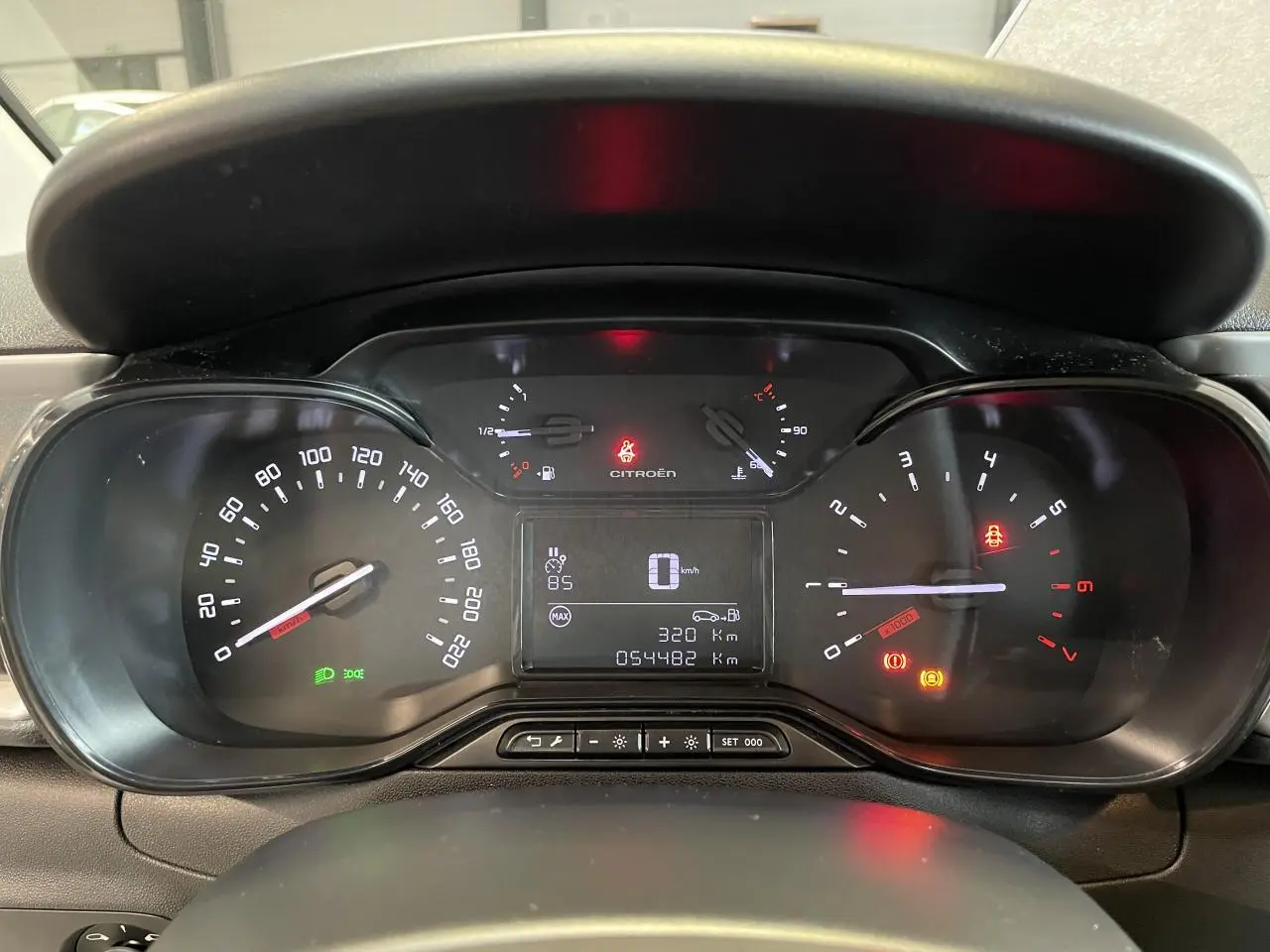 Vue rapprochée du tableau de bord numérique de la Citroën C3 blanche, affichant le compteur et les voyants allumés.