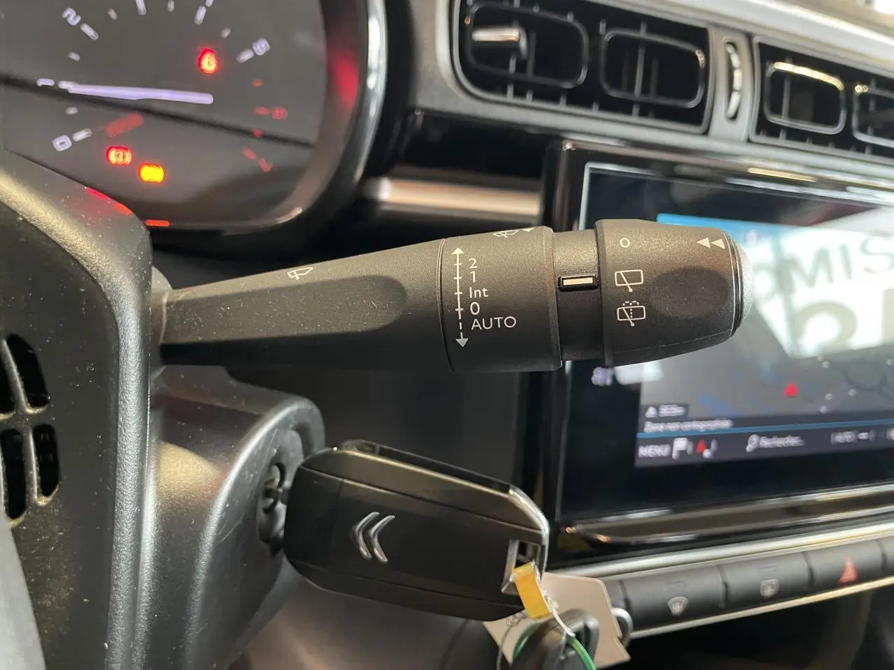 Gros plan sur la commande d’essuie-glace et clé insérée dans le contacteur d’une Citroën C3 2021, intérieur noir.