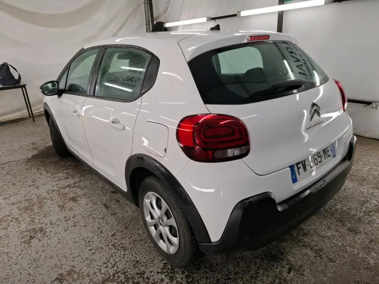 Vue 3/4 arrière droite d'une Citroën C3 blanche avec élargisseurs d'ailes noirs et feux arrière 3D dans un garage.