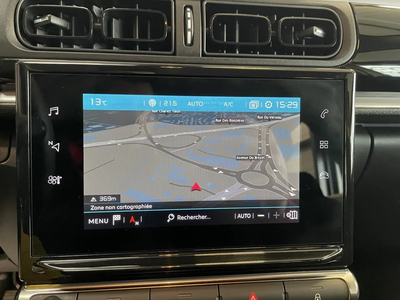 Écran tactile central avec navigation affichée sur tableau de bord noir brillant de Citroën C3 blanc, vue intérieure frontale.