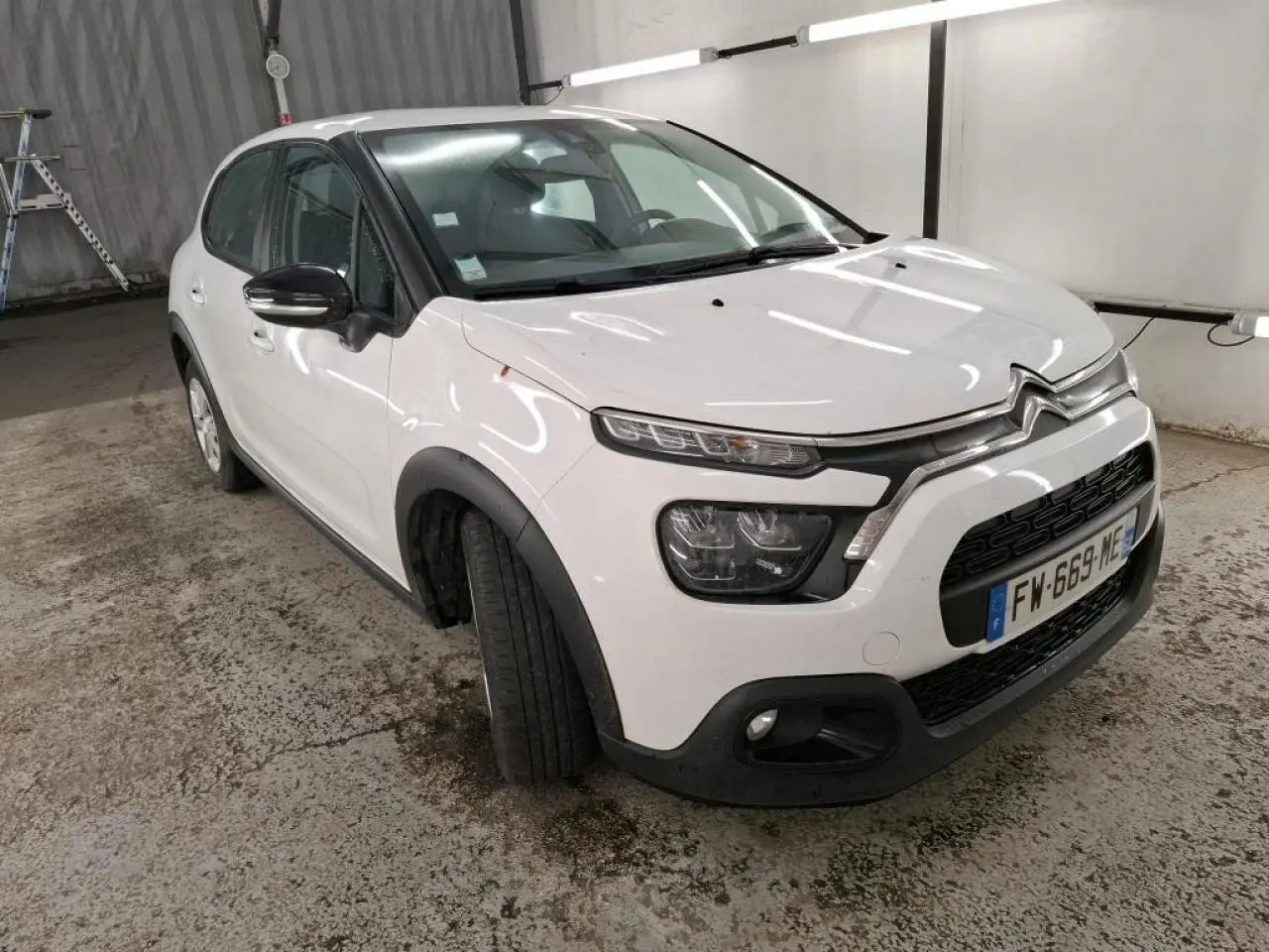 Citroën C3 blanc vue 3/4 avant droit avec coques de rétroviseurs noires et élargisseurs d'ailes noirs.