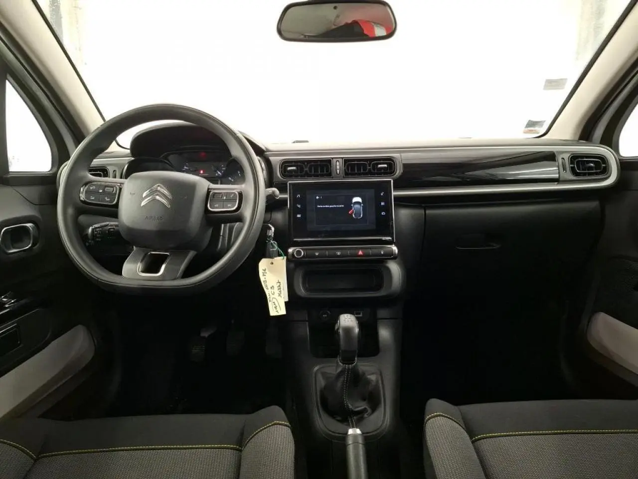 Vue intérieure avant de la Citroën C3 blanche, tableau de bord noir brillant avec écran tactile et volant multifonction.