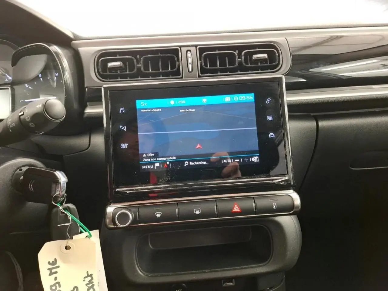 Vue rapprochée de la console centrale noire brillante avec écran tactile et aérateurs rectangulaires d'une Citroën C3 blanche.