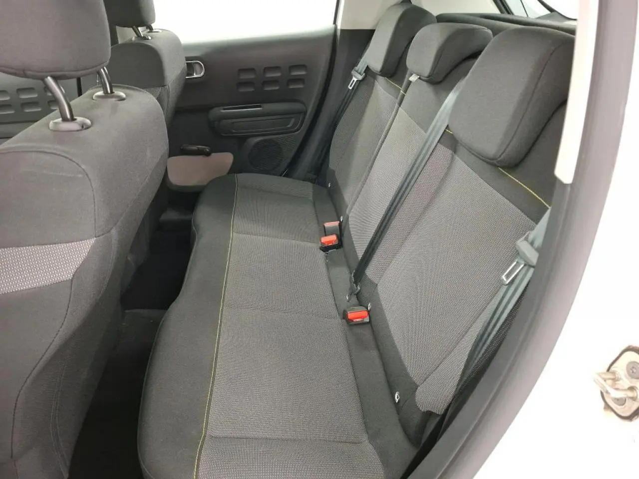 Vue intérieure côté droit de la banquette arrière tissu gris avec ceintures et appuie-têtes d'une Citroën C3 blanche.
