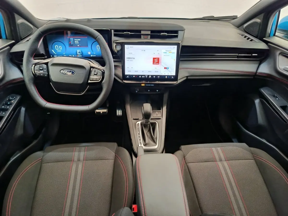 Vue intérieure avant du Ford Puma 2025, tableau de bord noir avec écran tactile central et volant multifonctions cuir.