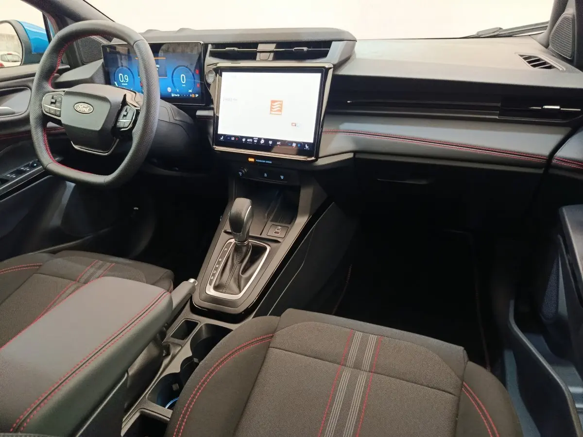 Vue intérieure avant de la Ford Puma 2025, tableau de bord avec écran tactile central et volant multifonctions cuir noir.