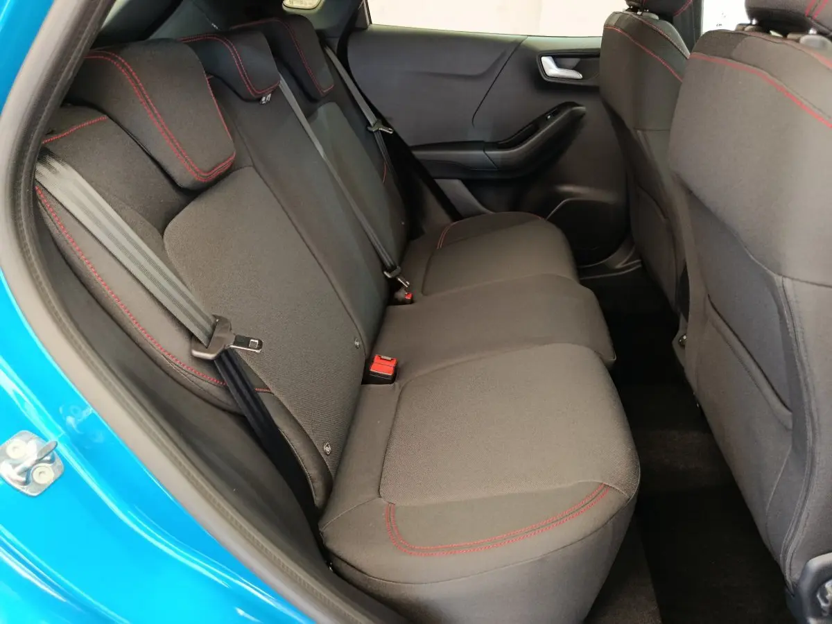 Vue intérieure côté gauche sur la banquette arrière noire avec surpiqûres rouges du Ford Puma bleu 2025 ST-LINE.