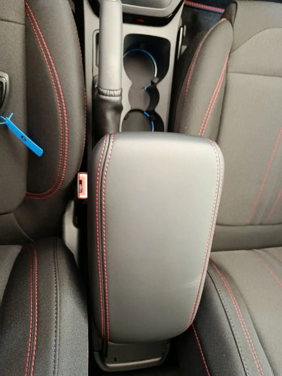 Vue plongeante sur l'accoudoir central noir avec surpiqûres rouges entre les sièges avant du Ford Puma ST-LINE.