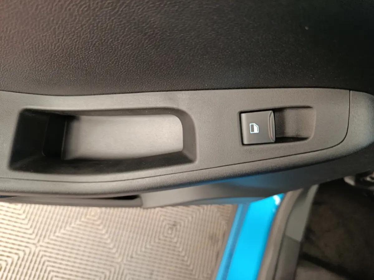 Gros plan sur la poignée intérieure de porte côté droit du Ford Puma bleu, avec bouton de verrouillage des vitres.