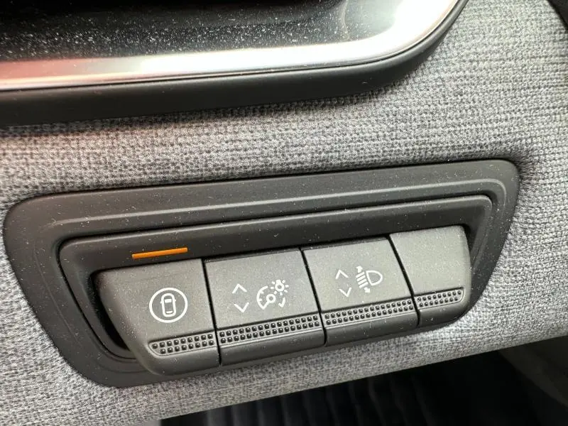 Gros plan sur les commandes de réglage d’éclairage et verrouillage intérieur sur panneau gris d’une Renault Clio 2025.