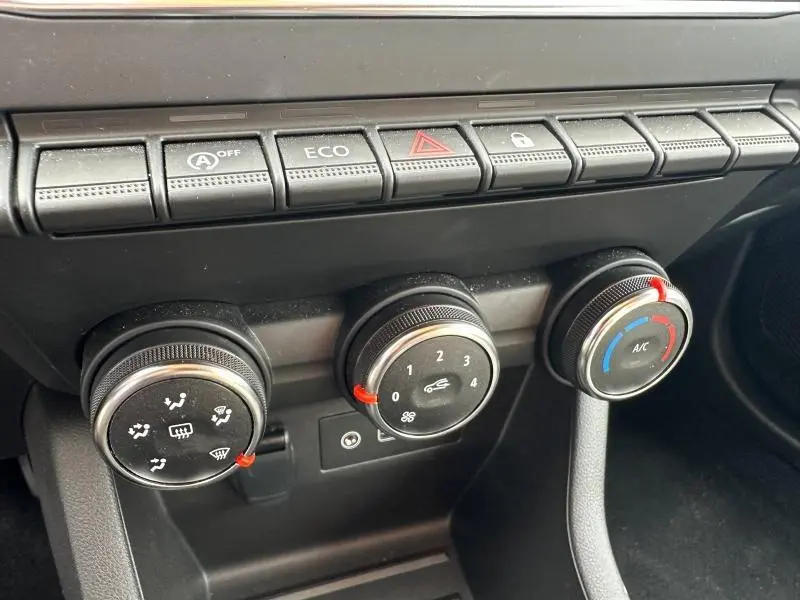 Gros plan sur les commandes de climatisation et les boutons de fonction du tableau de bord noir de la Renault Clio 2025.