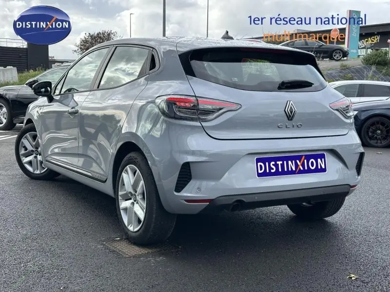 Vue 3/4 arrière droite d'une Renault Clio 2025 gris clair, avec feux arrière LED et logo distinctif au centre du hayon.