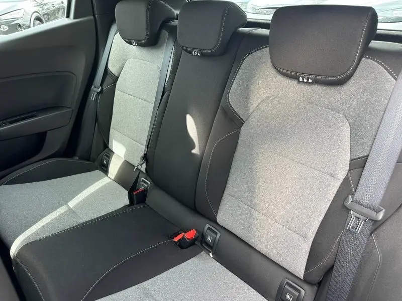 Vue intérieure des sièges arrière gris clair et noir de la Renault Clio 2025, montrant les appuie-têtes et ceintures de sécurité.