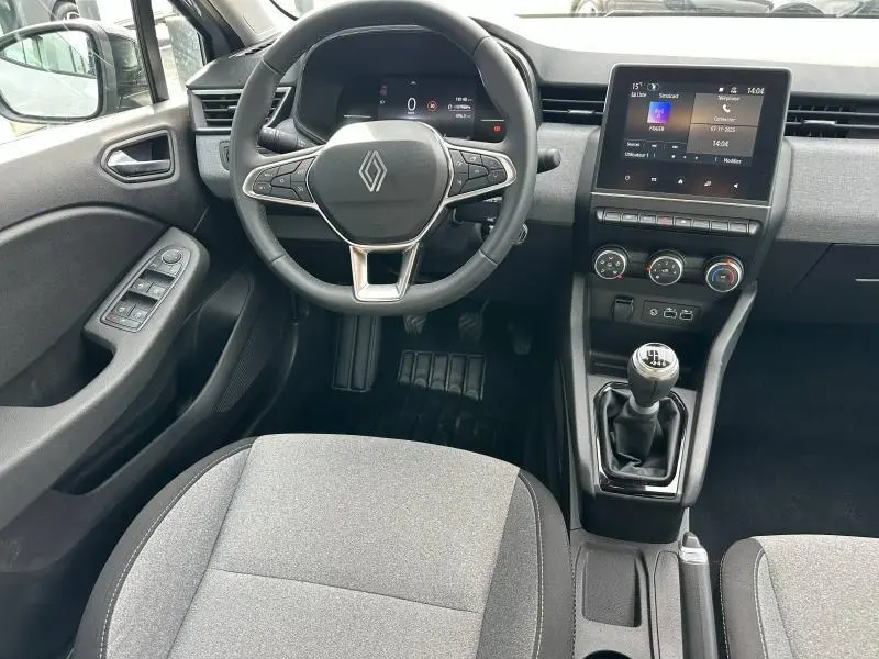 Vue intérieure de face du poste de conduite de la Renault Clio 2025, volant multifonction et levier de vitesse manuel visibles.