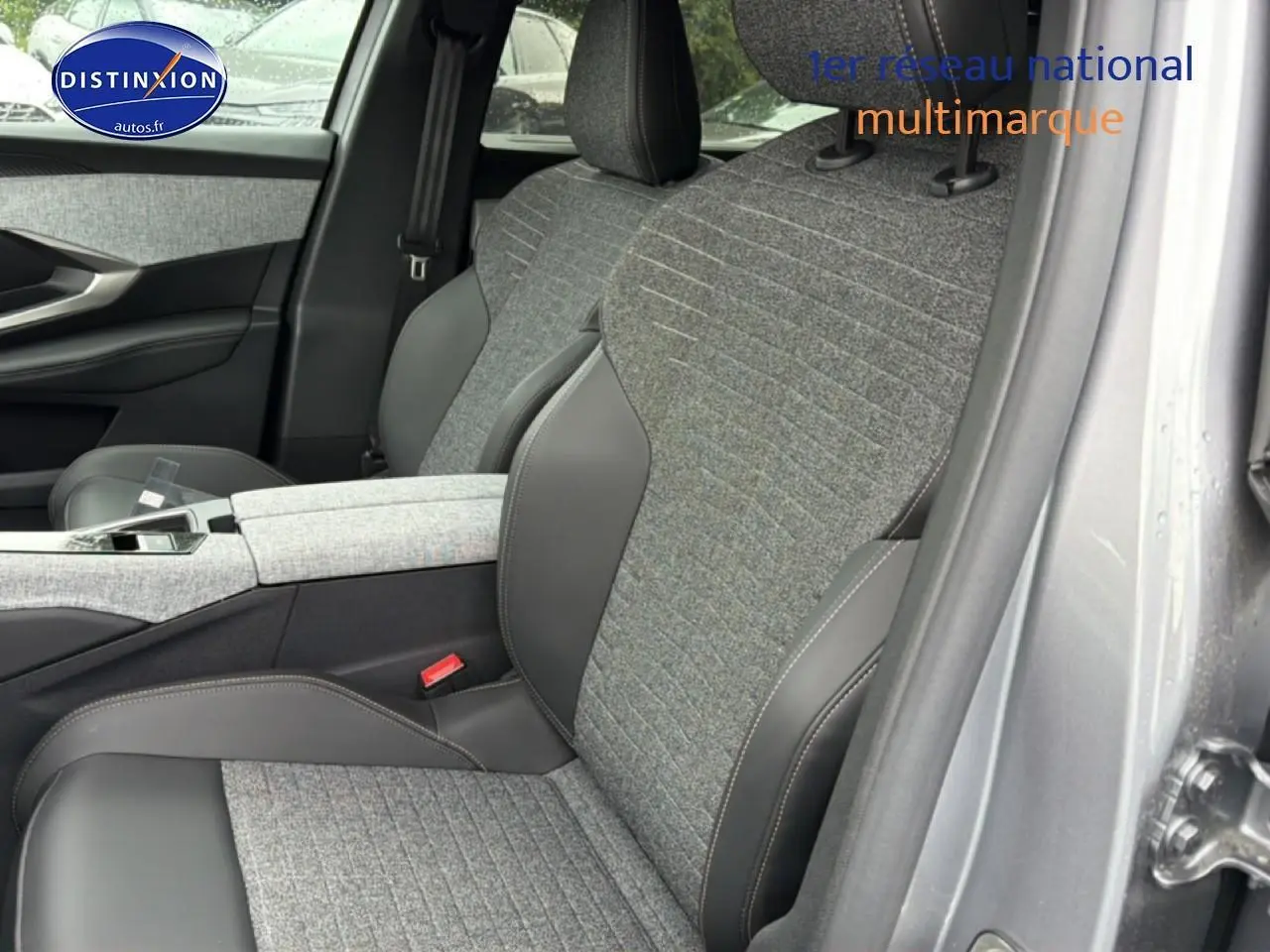 Gros plan sur les sièges avant gris tissu et cuir du Peugeot 5008 Hybrid 145 allure e-dcs6, avec accoudoir central.