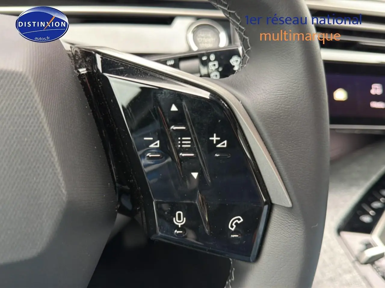 Gros plan sur les commandes vocales et audio au volant cuir du Peugeot 5008 gris Artense, intérieur moderne.
