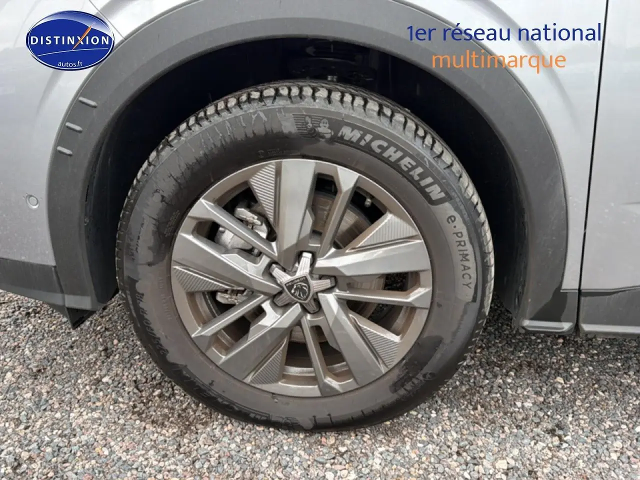 Gros plan sur la roue avant gauche avec jante alu et logo Peugeot du SUV 5008 gris Artense.