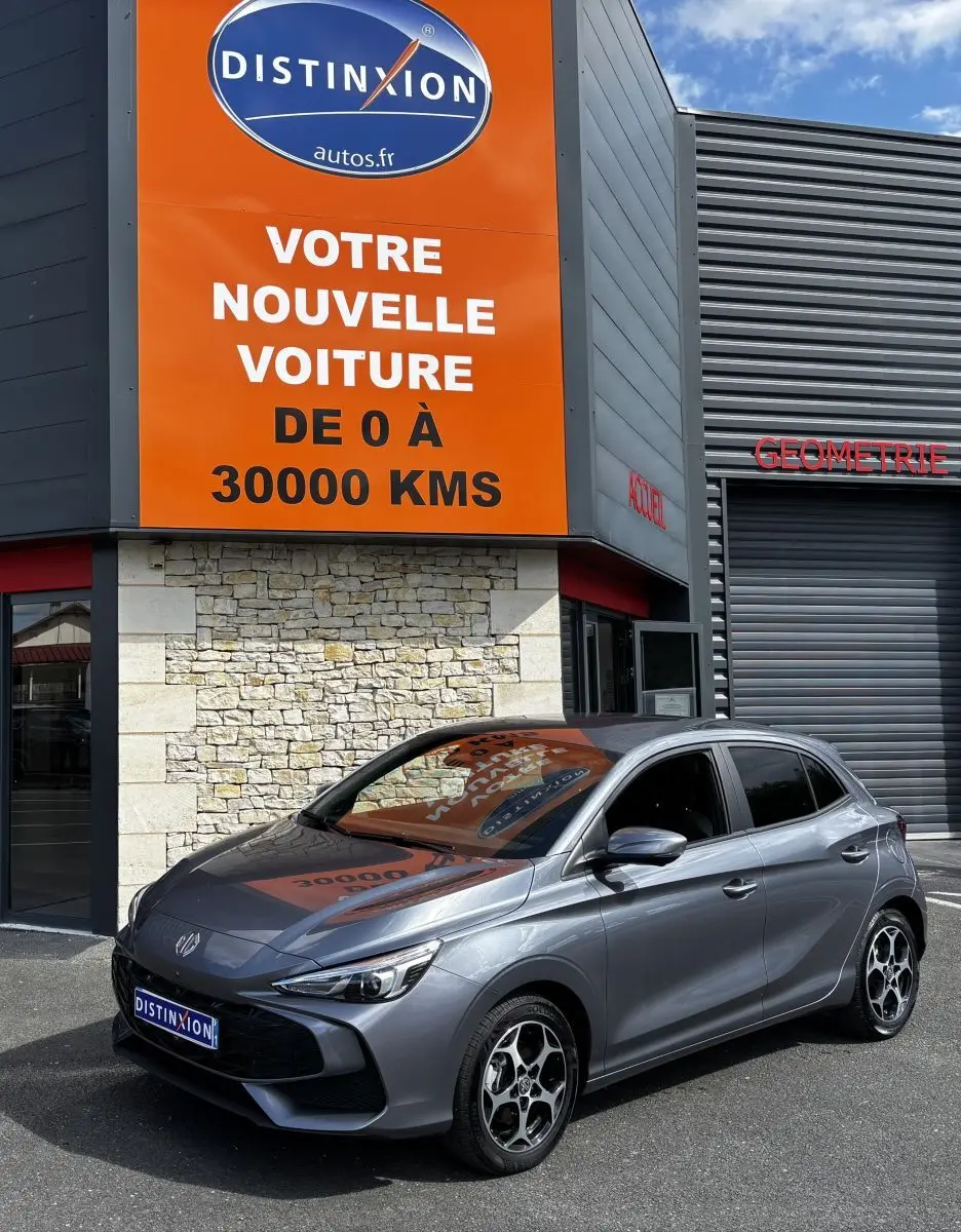 MG3 1.5L Hybrid+ Luxury gris clair vu en 3/4 avant droit devant un bâtiment commercial.