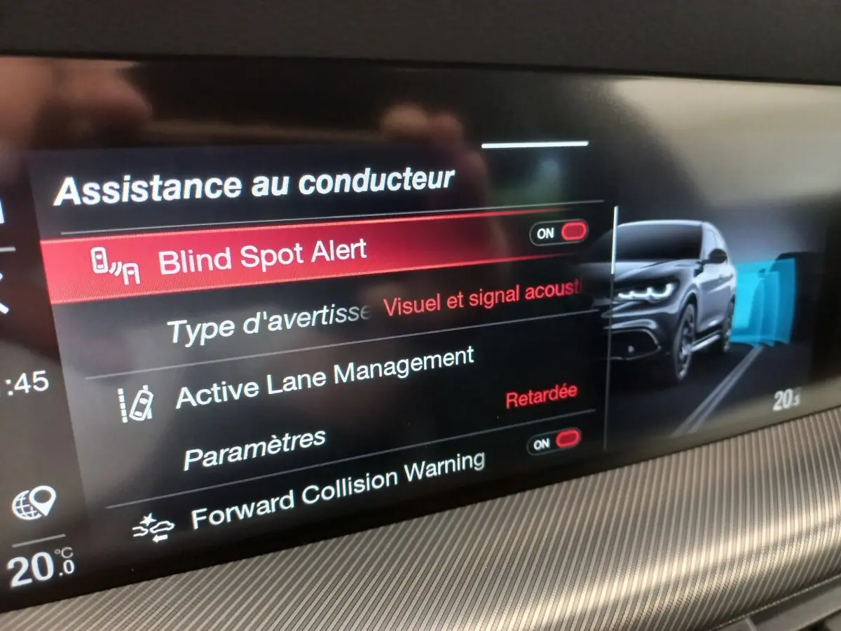 Écran tactile intérieur montrant les aides à la conduite avec illustration d’un Alfa Romeo Stelvio gris foncé en vue 3/4 avant.