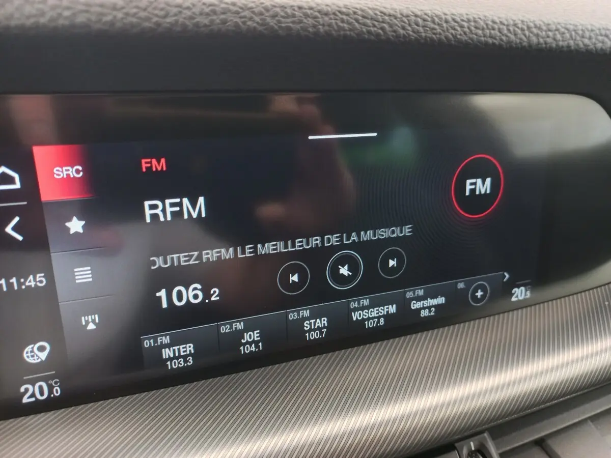 Gros plan sur l'écran tactile central du tableau de bord gris foncé de l'Alfa Romeo Stelvio 2024 affichant la radio FM.