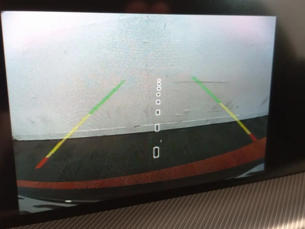 Vue caméra de recul arrière avec guidage coloré sur fond gris, sans visibilité directe du véhicule.