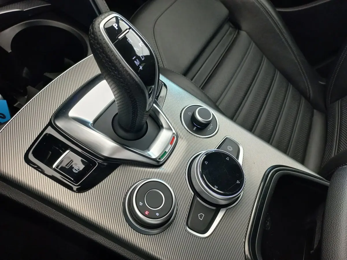 Gros plan sur la console centrale grise et le levier de vitesses automatique de l'Alfa Romeo Stelvio Sprint 2024, intérieur cuir noir.