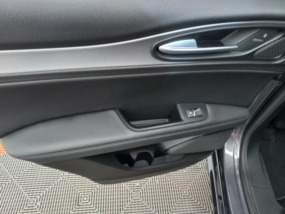 Vue rapprochée de la porte côté droit gris foncé de l'Alfa Romeo Stelvio 2024 avec poignée alu et commande de vitre.
