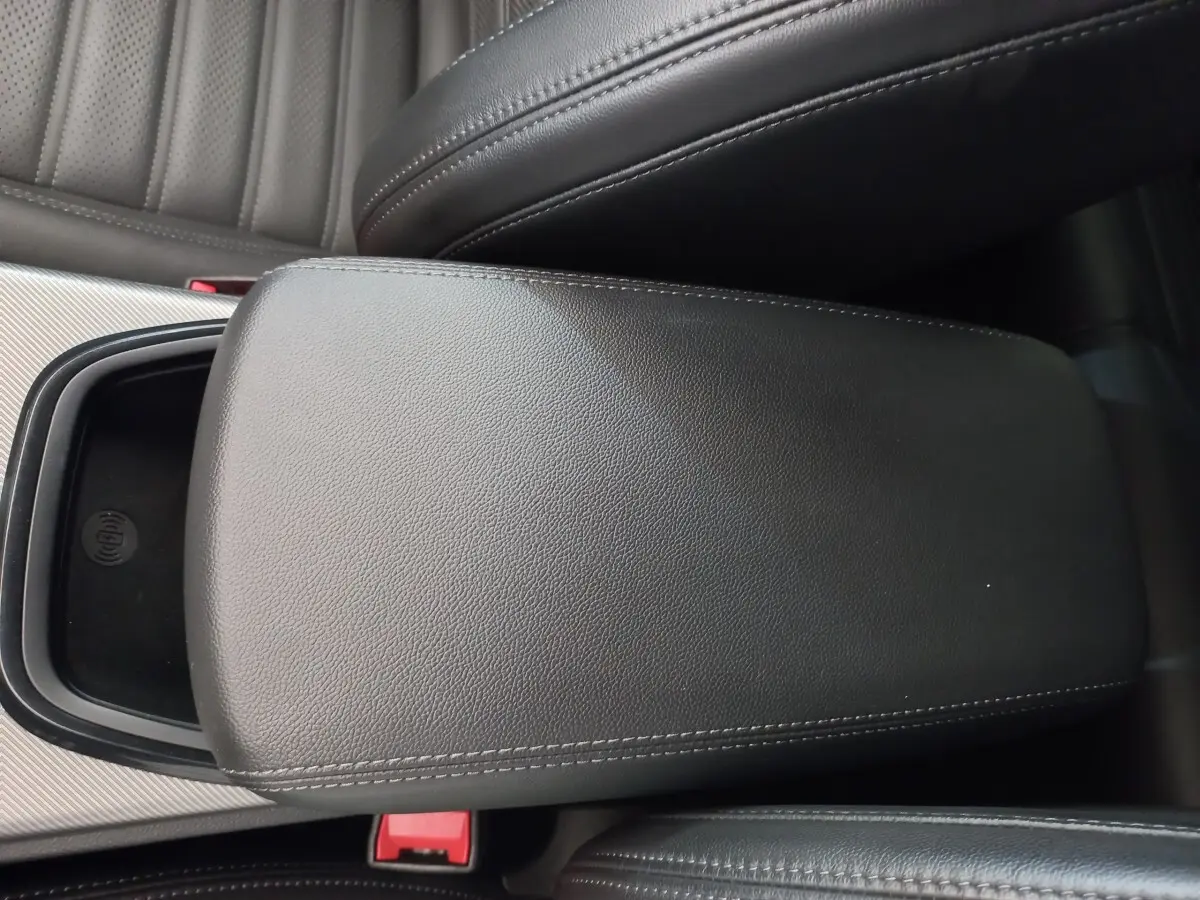 Gros plan sur l'accoudoir central en cuir noir de l'Alfa Romeo Stelvio 2024 avec zone de recharge sans fil visible.