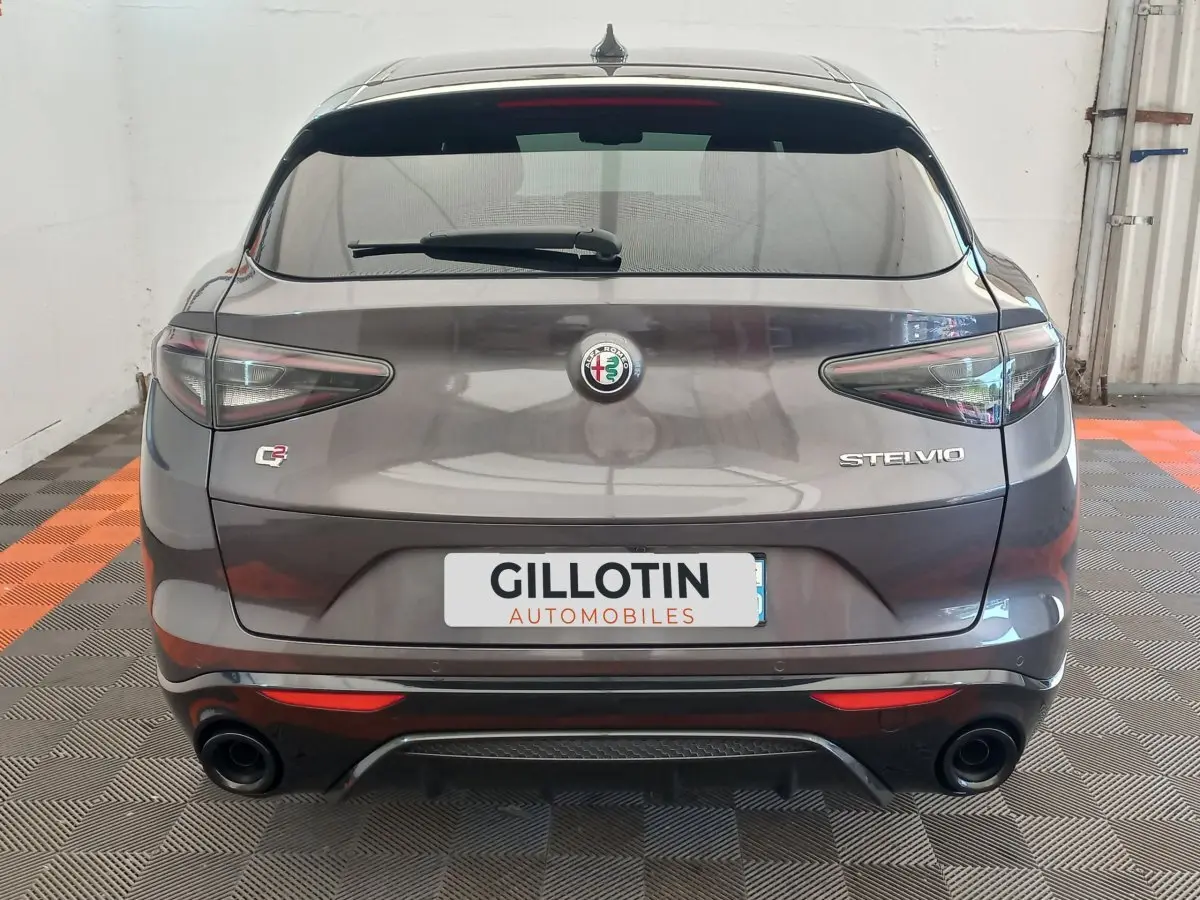Vue arrière d'un Alfa Romeo Stelvio gris foncé avec double sortie d'échappement et feux arrière LED distinctifs.