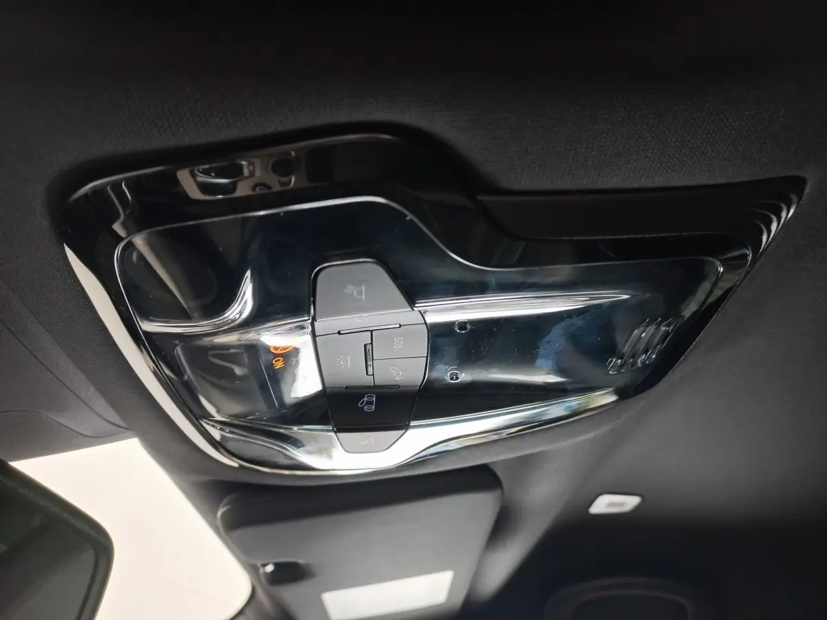 Vue intérieure en plongée du plafonnier noir brillant avec commandes d’éclairage et bouton SOS de l'Alfa Romeo Stelvio gris foncé.