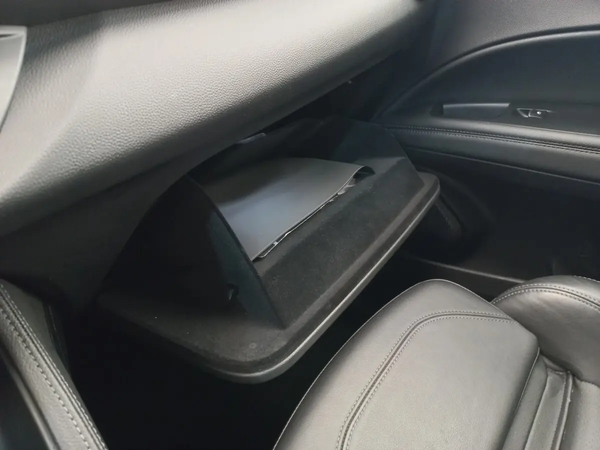 Vue intérieure côté passager de la boîte à gants ouverte avec revêtement noir dans l'Alfa Romeo Stelvio gris foncé.