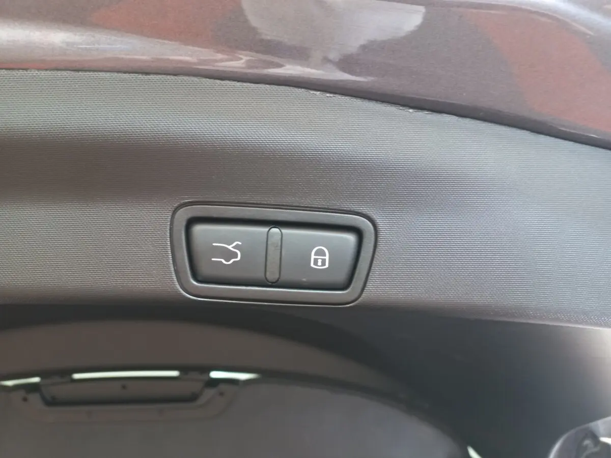 Gros plan sur les boutons d'ouverture et de verrouillage du coffre d'un Alfa Romeo Stelvio gris foncé, vue intérieure arrière.