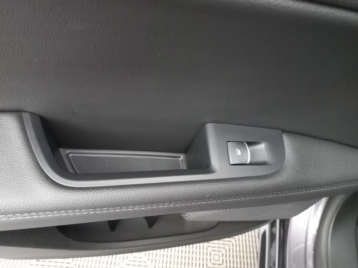 Détail de la poignée intérieure de porte côté gauche en cuir noir avec bouton de verrouillage, Alfa Romeo Stelvio gris foncé.