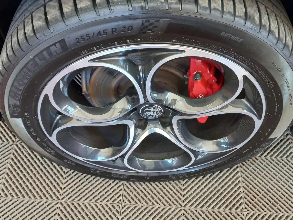Gros plan sur la roue avant droite de l'Alfa Romeo Stelvio gris foncé, avec étrier de frein rouge visible.