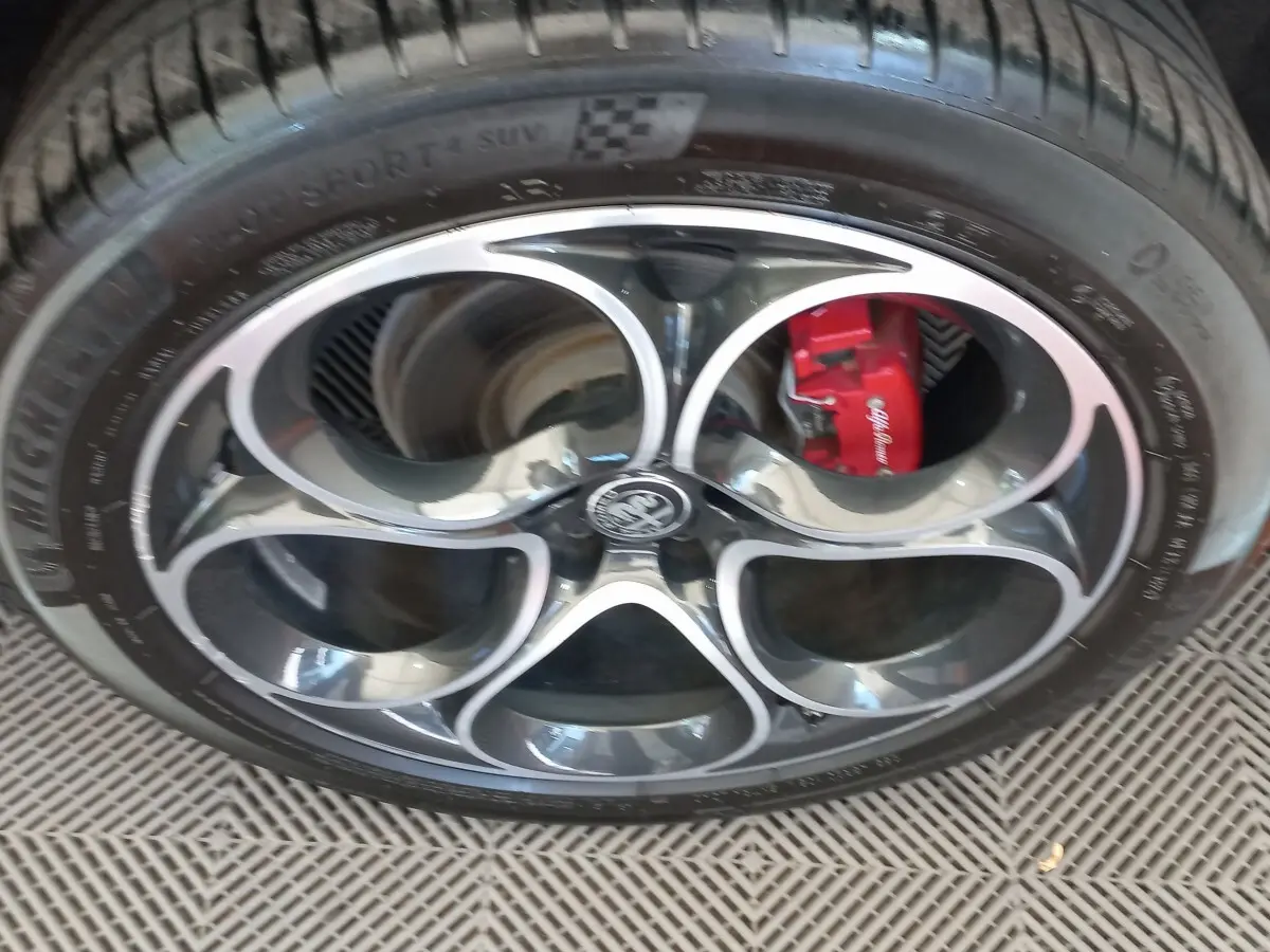 Gros plan sur la jante alu noire et argentée d’un Alfa Romeo Stelvio 2024 avec étrier de frein rouge visible.