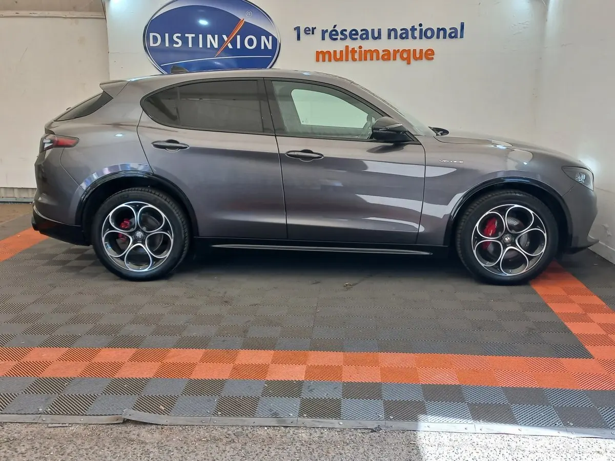 Vue de profil côté gauche d’un Alfa Romeo Stelvio gris foncé avec jantes distinctives et étriers de frein rouges.