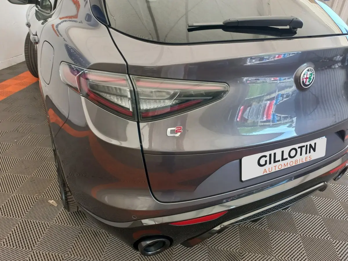 Vue 3/4 arrière droite de l'Alfa Romeo Stelvio gris foncé avec feux LED et double sortie d'échappement visible.