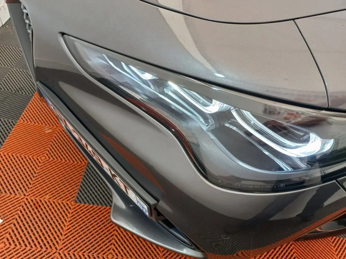Gros plan sur le phare avant droit d'un Alfa Romeo Stelvio gris foncé 2024 avec détails lumineux LED distinctifs.